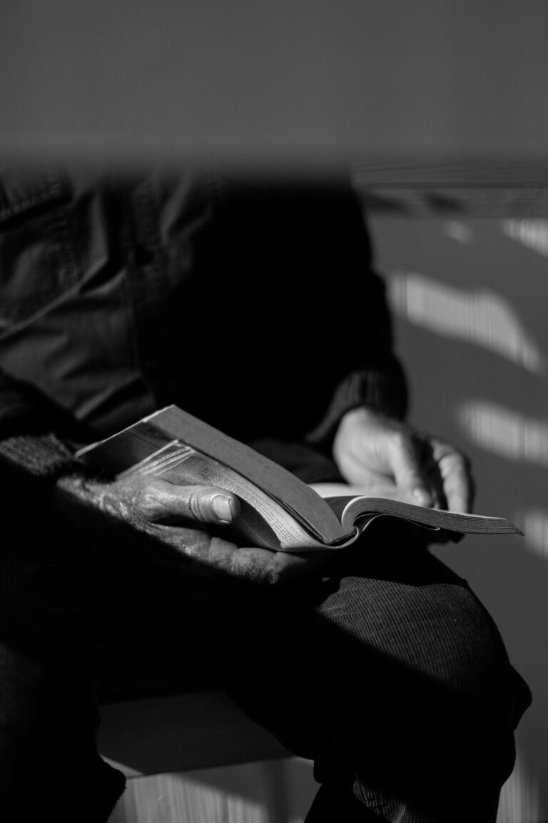 A senior adult reading a book, captured in black and white for a reflective mood.